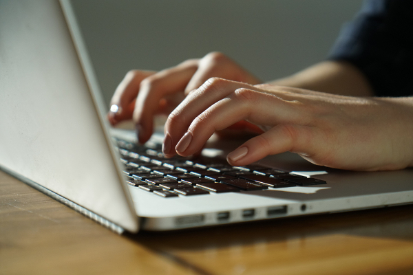 Hands typing on laptop